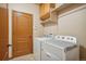 Bright laundry room featuring a full size washer and dryer with cabinet and shelf storage at 15947 Bridle Ridge Dr, Monument, CO 80132