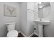 A half bathroom with a pedestal sink, round mirror, modern light fixture, and a geometric deer painting at 10010 E Gunnison Pl # 707, Aurora, CO 80247