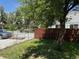 Exterior view with a gray SUV, wooden fence, white picket fence, and green grass at 8307 E 14Th Ave, Denver, CO 80220