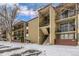 Three story condo building shows balconies and walkways in a snowy landscape at 2281 S Vaughn Way # 316A, Aurora, CO 80014