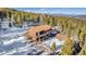 Aerial shot of a charming cabin featuring a spacious wooden deck and snow-covered surroundings at 255 Divide View Dr, Golden, CO 80403