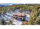 Drone view of a picturesque cabin nestled in a snowy forest with an expansive wooden deck at 255 Divide View Dr, Golden, CO 80403
