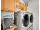 Laundry room with wood cabinets and modern washer and dryer at 9595 Elk Mountain Cir, Littleton, CO 80125