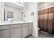 Well-lit bathroom with double sinks, a large mirror, and a shower with curtain at 3074 Kestrel St, Brighton, CO 80601