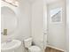 Compact bathroom with round mirror, pedestal sink, toilet, white walls, and window at 17120 E 90Th Pl, Commerce City, CO 80022