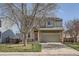 Two-story home with well-maintained lawn and two-car garage, featuring a red front door and stone accents at 9615 Lansing Cir, Commerce City, CO 80022