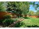 A well-maintained backyard featuring a lush lawn, a wooden fence, and a beautiful retaining wall garden at 5331 S Geneva Way, Englewood, CO 80111