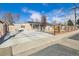 Charming exterior of home features a fenced yard, driveway, solar panels, and lush greenery at 4909 W Mississippi Ave, Denver, CO 80219