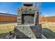 Close up of stone outdoor fireplace in backyard features metal grate, stone detail, and wood storage at 4909 W Mississippi Ave, Denver, CO 80219