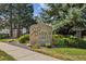 Stone sign for Arbor Green neighborhood surrounded by lush landscaping and mature trees at 8738 Chase Dr # 134, Arvada, CO 80003