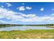Scenic view of the calm lake with grassy shoreline, mountain views, and a bright, cloudy sky at 8738 Chase Dr # 134, Arvada, CO 80003