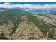 High altitude aerial view shows rolling hills and tree cover of the surrounding area at 23778 Inca Rd, Indian Hills, CO 80454