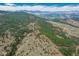 Breathtaking aerial view of a heavily wooded landscape with rolling hills and mountain views in the distance at 23778 Inca Rd, Indian Hills, CO 80454