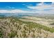 Scenic aerial view of a vast landscape with rolling hills, scattered trees and sprawling mountain ranges in the background at 23778 Inca Rd, Indian Hills, CO 80454