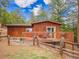 Cozy cabin exterior with a wooden deck and a charming fenced yard at 23778 Inca Rd, Indian Hills, CO 80454