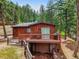 Two story cabin with wooden deck and drive in garage nestled among the trees at 23778 Inca Rd, Indian Hills, CO 80454