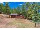 Cozy cabin with wood siding and a charming deck surrounded by lush greenery at 23778 Inca Rd, Indian Hills, CO 80454