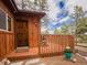Wooden home includes a cozy wooden porch with a wooden railing and potted plants at 23778 Inca Rd, Indian Hills, CO 80454