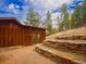 Exterior view of a wooded home with wooden siding, stepping stones, and stone retaining wall at 23778 Inca Rd, Indian Hills, CO 80454
