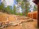Landscaped yard featuring stone and wood terraced steps, a shed, and natural surroundings at 23778 Inca Rd, Indian Hills, CO 80454