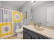 Well-lit bathroom featuring a vanity with a sink, a toilet, and a shower with a vibrant patterned curtain at 15157 E Nassau Ave, Aurora, CO 80014
