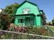 Charming two-story home with a bright green exterior and flourishing flower garden in front at 4047 Lowell Blvd, Denver, CO 80211