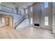 Spacious living room with a floor-to-ceiling stone fireplace, large windows, light wood floors, and an open staircase at 8724 Big Thompson St, Littleton, CO 80125