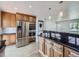 Spacious kitchen with wood cabinets, black countertops, stainless steel appliances and adjacent breakfast bar at 2830 E 99Th Way, Thornton, CO 80229