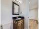 Charming powder room with a dark vanity, a framed mirror, and a white toilet, conveniently located off the main living area at 2830 E 99Th Way, Thornton, CO 80229
