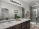 Bright bathroom featuring a double sink vanity, large mirror, and glass-enclosed shower at 5347 Warrior St, Frederick, CO 80504