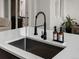 Modern kitchen sink with black faucet, white countertop, and soap dispensers at 5347 Warrior St, Frederick, CO 80504