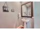 Cozy powder room with a pedestal sink, a decorative mirror, and framed artwork on the gray walls at 467 S Reed Ct, Lakewood, CO 80226