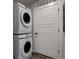 This modern laundry room features stacked washer and dryer units and a white paneled door at 1208 N Quitman St # 402, Denver, CO 80204