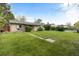 Large grassy backyard with mature trees, a small patio, and a brick house in the background at 8305 Eaton Way, Arvada, CO 80003