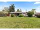 The large, well-maintained backyard features mature trees and a charming, covered patio area at 8305 Eaton Way, Arvada, CO 80003