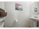 Cozy powder room featuring a pedestal sink, decorative mirror, and charming wall art at 892 Macaw St, Brighton, CO 80601