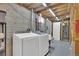 Functional laundry room featuring modern washer and dryer with exposed utilities and wooden framing at 1225 S Honey Way, Denver, CO 80224