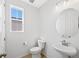 Half bathroom featuring a pedestal sink, toilet, and a window for natural light at 9175 Uravan Ct, Commerce City, CO 80022