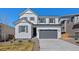 Charming two-story home with white siding, a gray garage door, and well-maintained landscaping at 9175 Uravan Ct, Commerce City, CO 80022