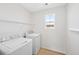 Bright laundry room featuring a washer, dryer, wire shelving and natural light from the window at 9175 Uravan Ct, Commerce City, CO 80022
