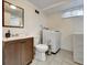 A compact bathroom with a toilet, sink, and washing machine, featuring neutral tile flooring at 10878 Grange Creek Dr, Thornton, CO 80233