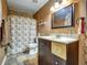 Cozy bathroom with vanity and shower featuring brown-toned walls and flooring, plus a floral shower curtain at 10878 Grange Creek Dr, Thornton, CO 80233