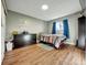 Simple bedroom with a window, dresser, and bed featuring light gray walls and wood-look vinyl flooring at 10878 Grange Creek Dr, Thornton, CO 80233