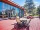 Outdoor wooden deck includes outdoor furniture and offers scenic views and full-wall glass doors to the interior at 8791 Grizzly Way, Evergreen, CO 80439