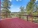 A spacious red deck with black metal railings showcases scenic mountain and countryside views at 8791 Grizzly Way, Evergreen, CO 80439
