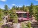 Modern mountain home nestled among pine trees features expansive glass walls, deck, and unique architectural design at 8791 Grizzly Way, Evergreen, CO 80439
