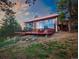 A modern mountain home featuring a wall of windows and a large deck with sunset sky backdrop at 8791 Grizzly Way, Evergreen, CO 80439