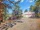 Home featuring a three-car garage and additional building with a red railed deck and gravel driveway at 8791 Grizzly Way, Evergreen, CO 80439