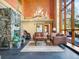 Living room with a stone fireplace, large windows, antler chandelier, and plush seating at 8791 Grizzly Way, Evergreen, CO 80439