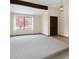 Bright living room with vaulted ceiling, beam, neutral carpet, and a large window framing a mature tree at 8133 W Quarto Ave, Littleton, CO 80128